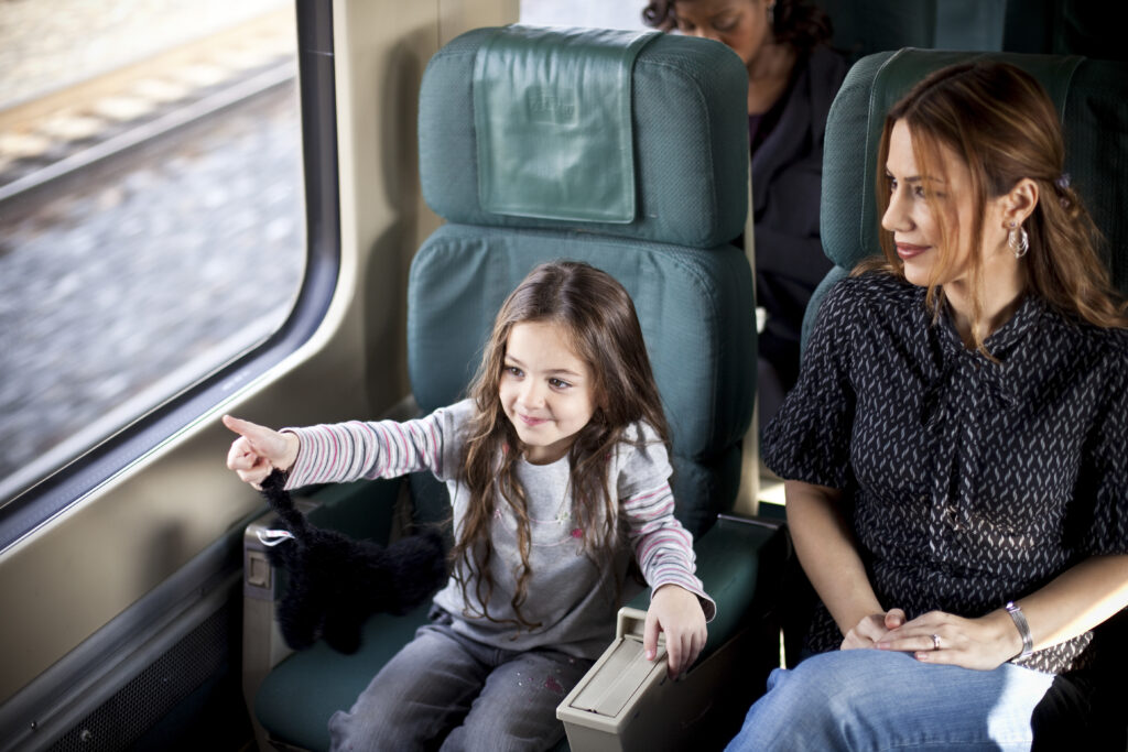 A child gives a thumbs up as they travel on a VIA Rail train.