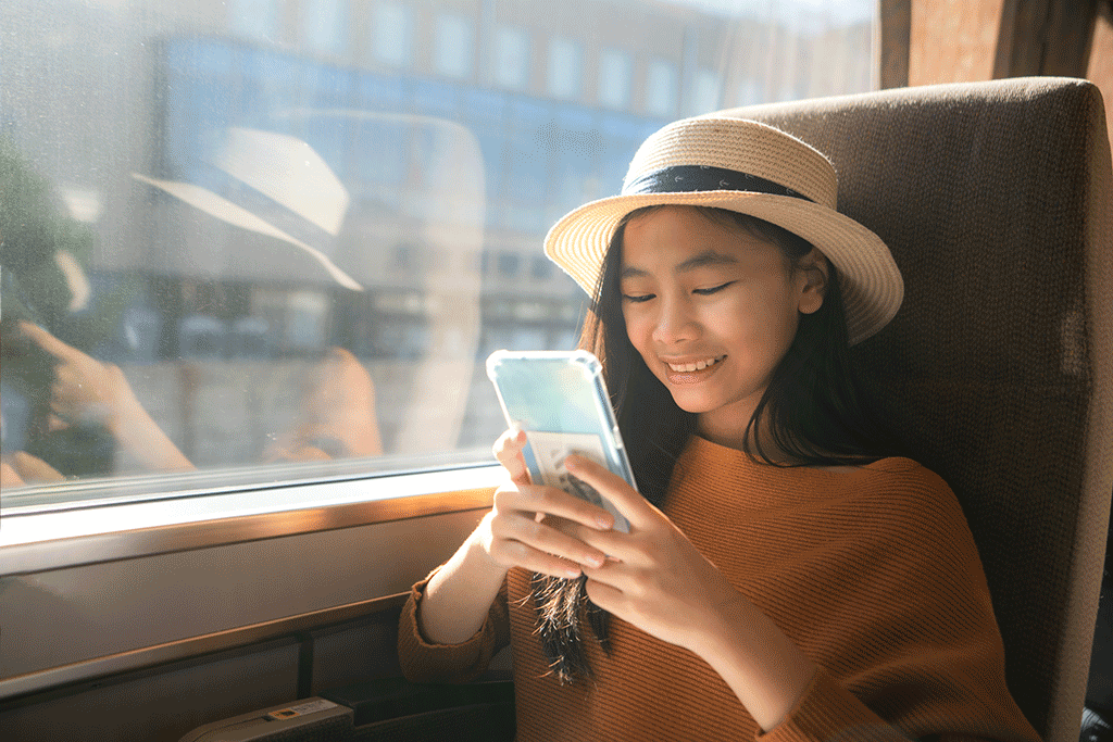 A person travelling on a train, looks at a smartphone.