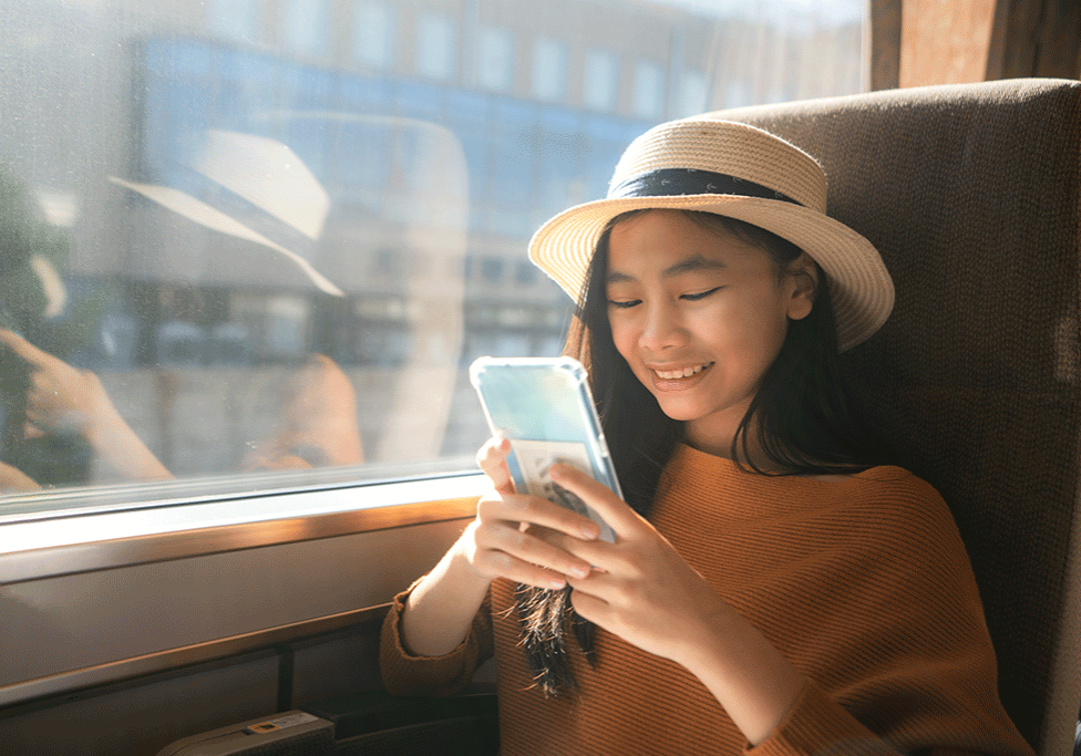 A person travelling on a train, looks at a smartphone.